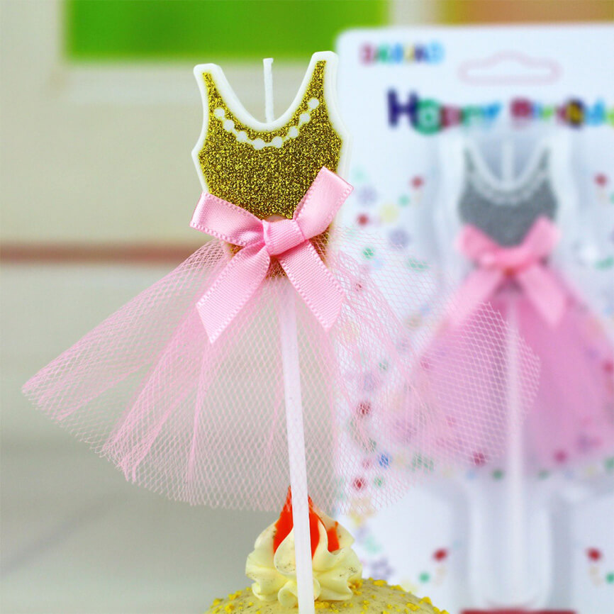 A candle shaped like a ballerinas tutu in gold